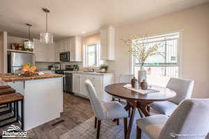 Kitchen featuring white cabinets, appliances with stainless steel finishes, a kitchen island, and wood counters