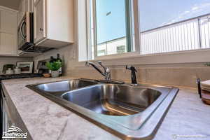 Interior details with appliances with stainless steel finishes, white cabinetry, and sink