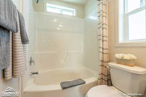 Bathroom with shower / bath combination with curtain and toilet