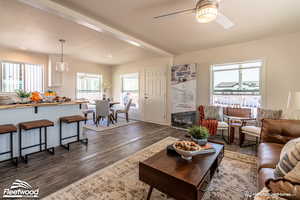 Living room featuring ceiling fan, dark hardwood / wood-style flooring, and beamed ceiling