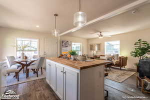 Kitchen featuring ceiling fan, white cabinetry, a kitchen island, hanging light fixtures, and butcher block counters