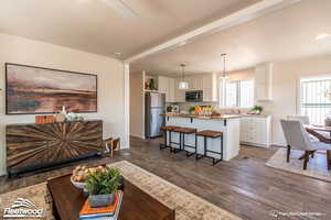 Kitchen featuring a center island, a kitchen breakfast bar, decorative light fixtures, white cabinetry, and stainless steel appliances