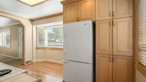 Kitchen featuring white fridge, crown molding, and light hardwood / wood-style flooring