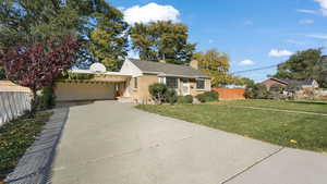 View of front of property featuring a front lawn and a carport