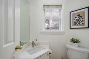 Main level half bathroom with vanity and toilet