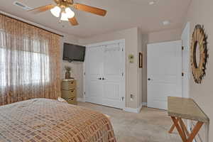 Carpeted bedroom featuring ceiling fan and a closet