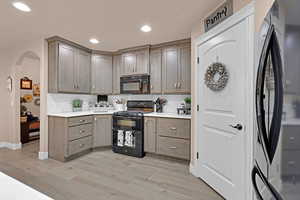 Kitchen with backsplash, black appliances, and light wood-type flooring