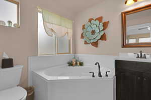 Bathroom with a tub to relax in, vanity, and toilet