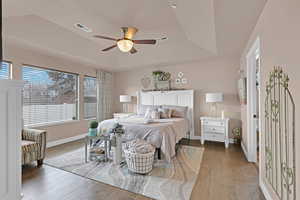 Bedroom featuring a tray ceiling, ceiling fan, and dark wood-type flooring