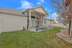 Rear view of house with a patio and a lawn