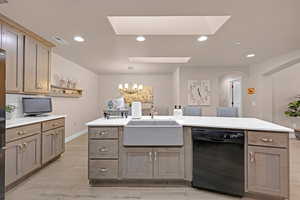 Kitchen with a skylight, sink, hanging light fixtures, black dishwasher, and a notable chandelier