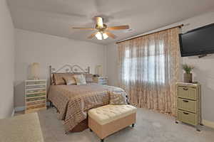 Carpeted bedroom featuring ceiling fan