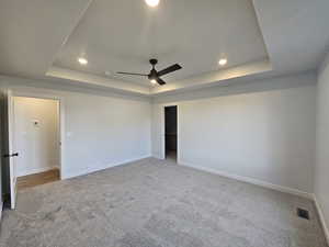 Unfurnished room with carpet floors, a tray ceiling, and ceiling fan