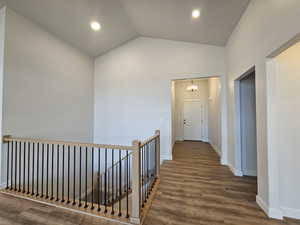 Hall featuring wood-type flooring, lofted ceiling, and a chandelier