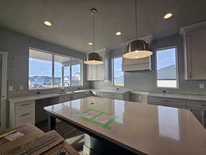 Kitchen with light stone countertops, decorative backsplash, sink, and pendant lighting