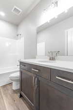 Full bathroom with hardwood / wood-style flooring, vanity, tub / shower combination, and toilet