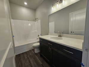 Full bathroom with hardwood / wood-style floors, vanity, toilet, and shower / bathing tub combination