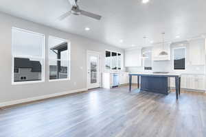 Kitchen with a breakfast bar, white cabinetry, a center island, hanging light fixtures, and custom range hood