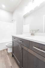 Full bathroom with shower / bath combination, wood-type flooring, vanity, and toilet