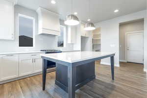 Kitchen with white cabinetry, a center island, pendant lighting, and stainless steel range