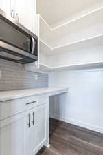 Kitchen with white cabinetry, backsplash, and dark hardwood / wood-style flooring