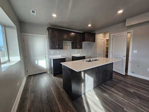 Kitchen featuring a textured ceiling, dark brown cabinetry, sink, dark hardwood / wood-style floors, and a kitchen island