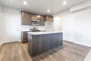 Kitchen with dark brown cabinets, appliances with stainless steel finishes, sink, and a center island with sink