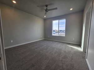 Spare room with dark colored carpet and ceiling fan