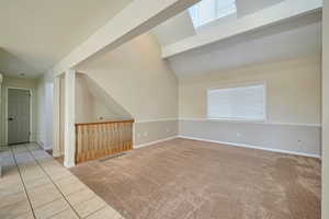 Additional living space with light tile patterned flooring and lofted ceiling with beams