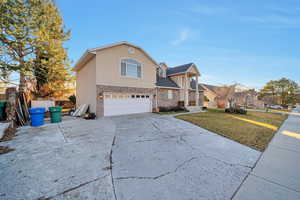 View of front property featuring a garage and a front lawn