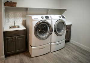 Laundry room with washer and dryer, cabinets, light wood-like tile flooring, and sink