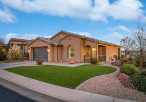 This beautiful home is the Topaz floor plan by Cole West Home in Brio. The exterior elevation is Spanish-style with a large curved central window, gated front porch, two car garage, and low maintenance turf.