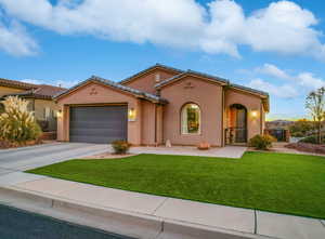 This beautiful home is the Topaz floor plan by Cole West Home in Brio. The exterior elevation is Spanish-style with a large curved central window, gated front porch, two car garage, and low maintenance turf.