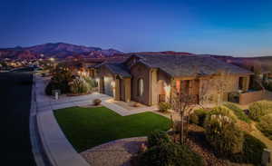 Spanish-style home featuring turf, a mountain view, and garage