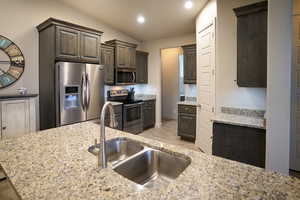 Kitchen featuring granite countertops, stainless steel appliances, and vaulted ceiling.