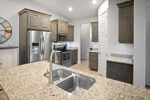 Kitchen featuring a vaulted ceiling, granite counters, and stainless steel appliances.