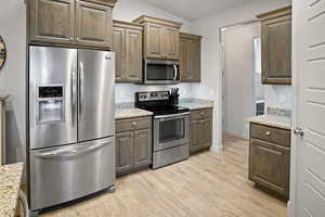 Kitchen featuring a vaulted ceiling, granite counters, and stainless steel appliances.