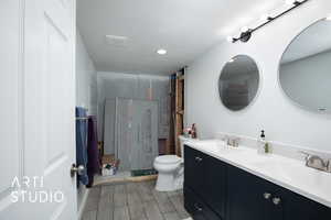 Bathroom with a shower with door, vanity, a textured ceiling, and toilet