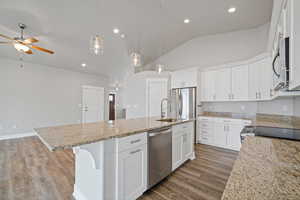 Kitchen with a kitchen island with sink, white cabinets, pendant lighting, and appliances with stainless steel finishes