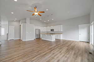 Unfurnished living room with ceiling fan, high vaulted ceiling, and light hardwood / wood-style flooring