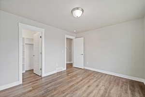 Unfurnished bedroom featuring a walk in closet, light hardwood / wood-style flooring, and a closet