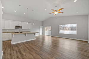 Kitchen featuring pendant lighting, white cabinetry, a healthy amount of sunlight, and an island with sink