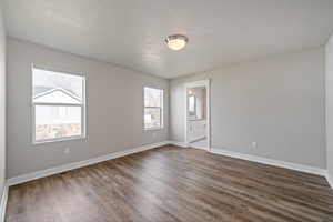 Empty room featuring a textured ceiling and dark hardwood / wood-style floors