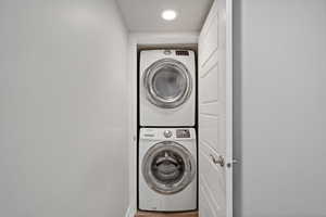 Clothes washing area featuring stacked washer and clothes dryer