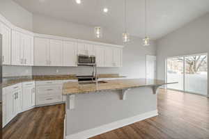 Kitchen with white cabinetry, sink, an island with sink, and decorative light fixtures