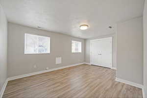 Unfurnished bedroom featuring a closet, light hardwood / wood-style flooring, and a textured ceiling