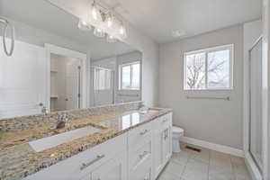 Bathroom featuring tile patterned floors, vanity, a shower with shower door, and toilet