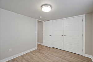 Unfurnished bedroom with light hardwood / wood-style floors, a textured ceiling, and a closet