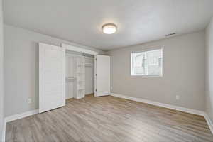 Unfurnished bedroom with a textured ceiling, light hardwood / wood-style floors, and a closet