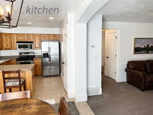 Kitchen with light tile patterned floors, a textured ceiling, and appliances with stainless steel finishes